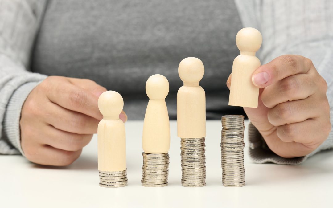 Wooden figures on stacked coins, symbolising income disparity.