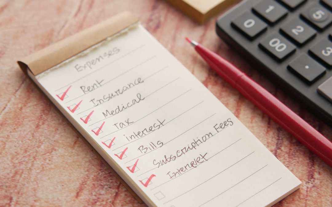 Checklist of expenses near calculator and pen.